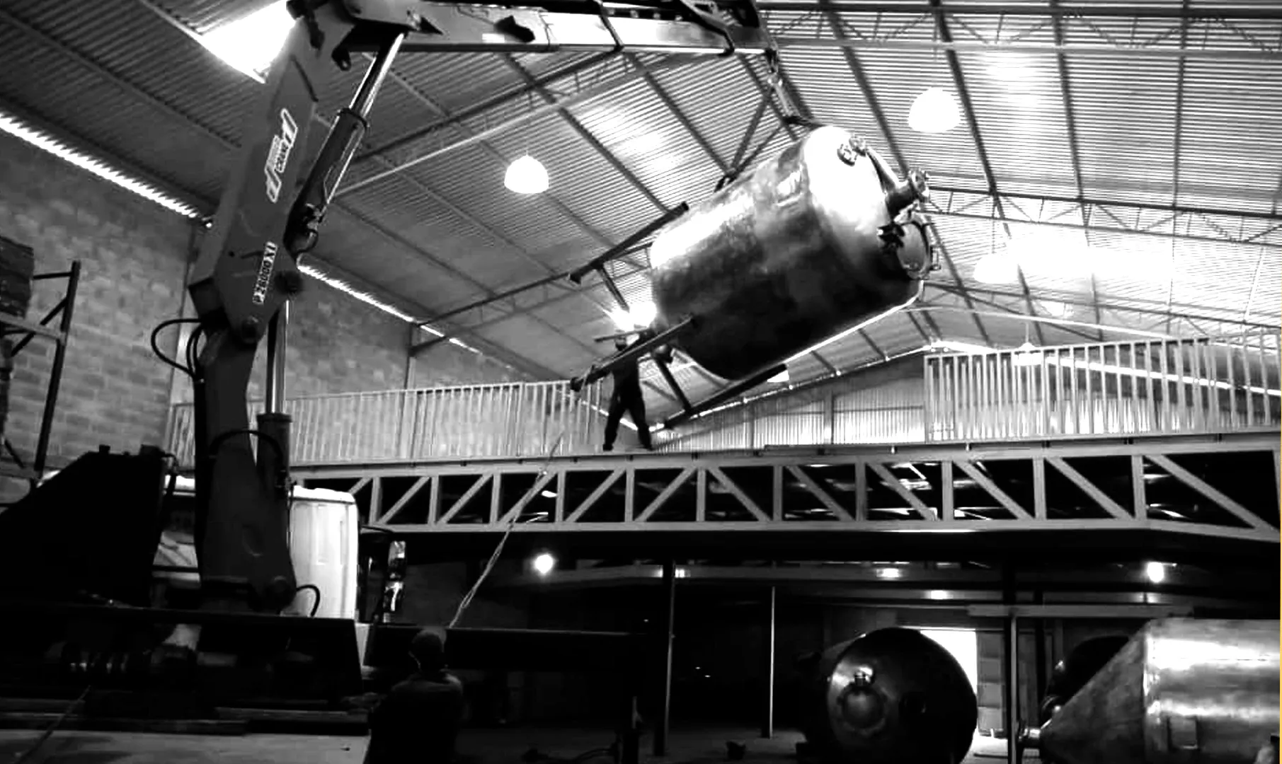 Grúa izando un tanque industrial dentro de un galpón